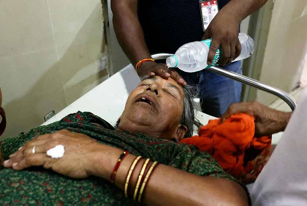 Seorang kakitangan hospital mencurah air di muka pesakit yang mengalami strok haba di hospital kerajaan di New Delhi. - AFP