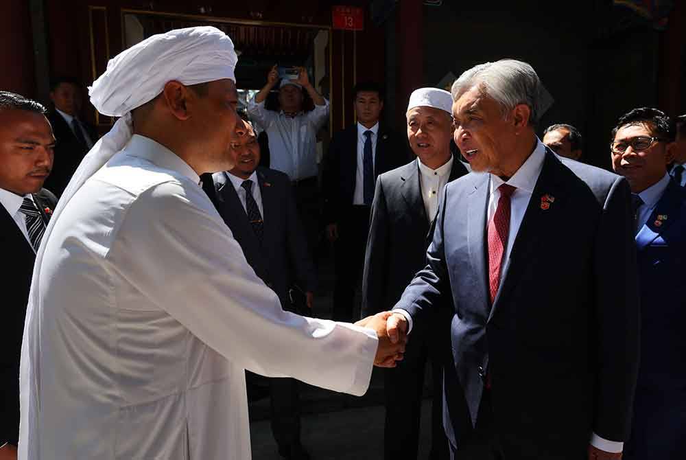 Ahmad Zahid (kanana) bersalaman dengan Imam Masjid Dongsi (kiri) Qian Aidong ketika hadir untuk menunaikan solat Jumaat di Masjid Dongsi hari ini. Foto Bernama