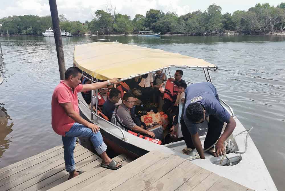 Khairul Azhar (kanan) menyambut pelancong yang tiba di Jeti Merang di Setiu.