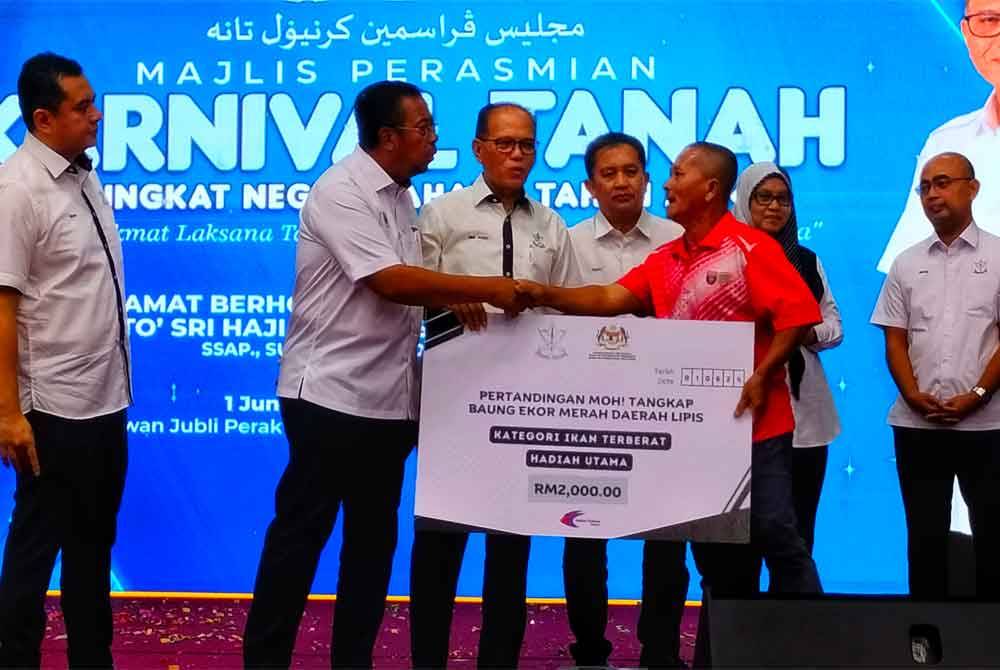 Abdul Jalil (Merah) menerima replika cek juara bernilai RM2,000 yang disampaikan Menteri Besar, Datuk Seri Wan Rosdy Wan Ismail (tiga dari kiri).