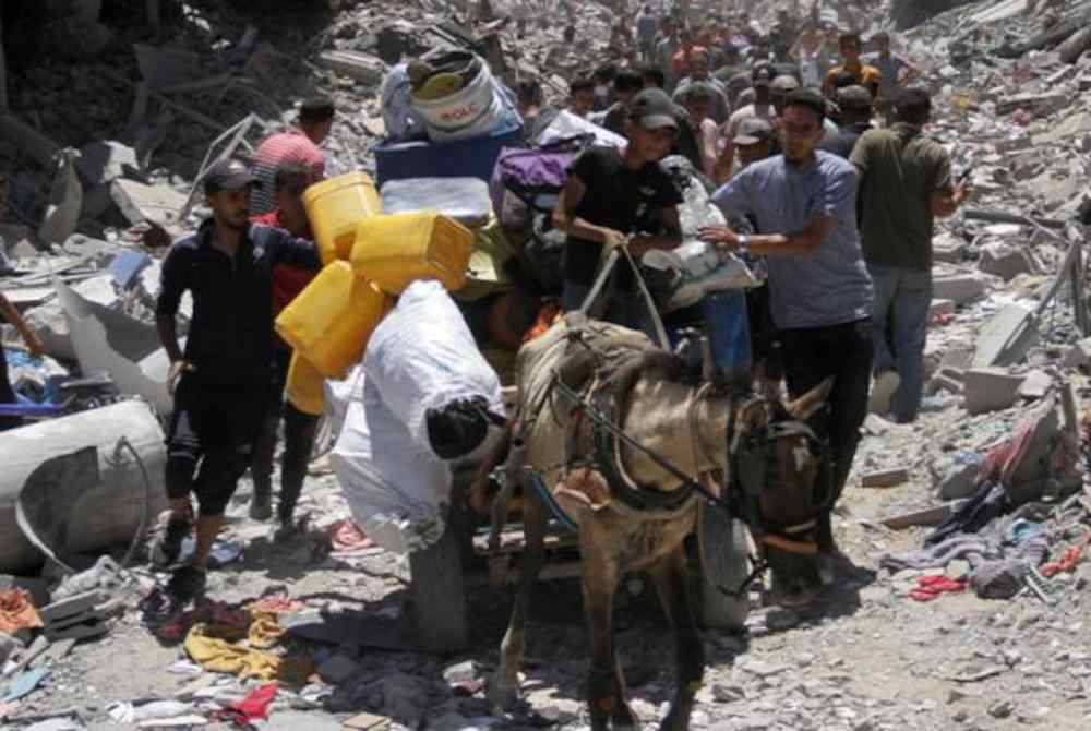 Orang ramai memeriksa kemusnahan pada bangunan yang diserang tentera rejim Zionis Israel di kem pelarian Jabalia. Foto Reuters