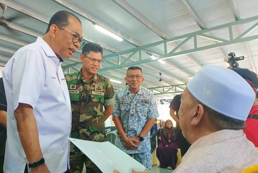 Mohamed Khaled (kiri) menyantuni waris keluarga Allahyarham Nor Rahiza Anuar yang diwakili bapanya, Anuar Hassan dan suami, Mohd Azinor Azizan.