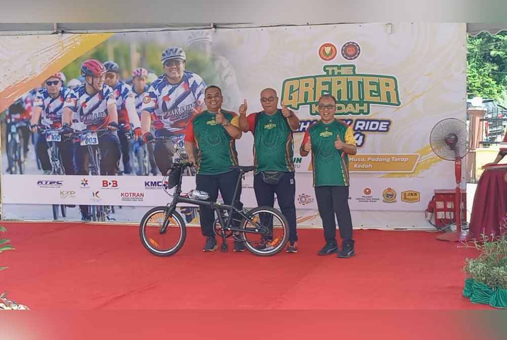 Muhammad Sanusi (kiri) menyampaikan hadiah cabutan bertuah kepada peserta kayuhan padaprogram The Greater Kedah Charity Ride 2024 di Masjid Kampung Musa, mukim Pedu, di sini, pada Sabtu.