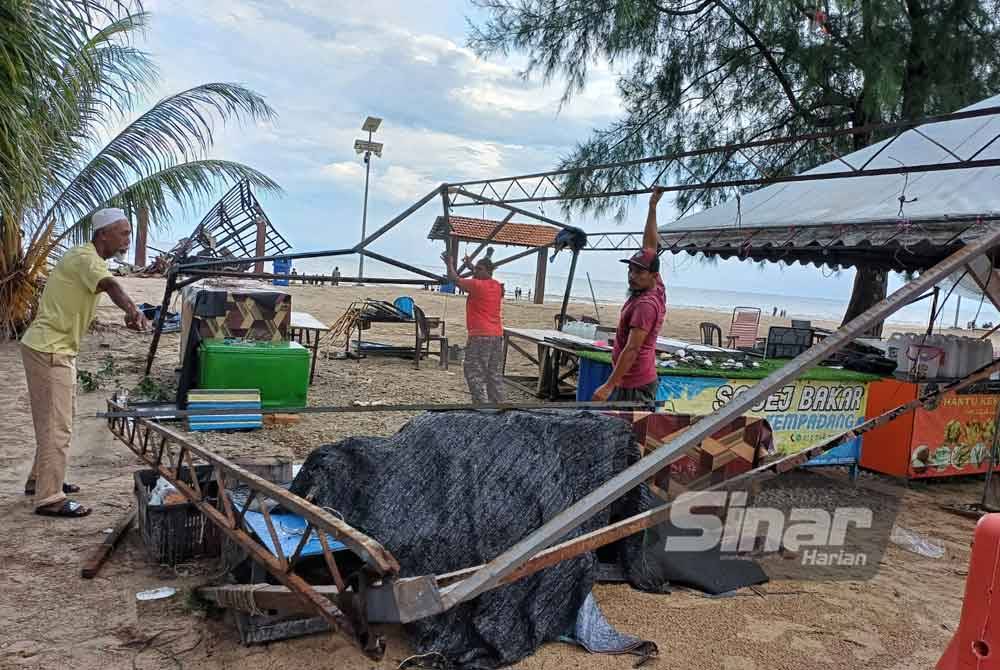 Muhammad Shafiq (kanan) sedang membuka batang besi kanopi yang roboh akibat dipikul ribut kuat pada petang Sabtu.