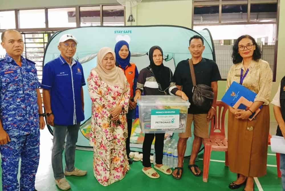 Khirin-Nisa (tiga dari kiri) ketika menyerahkan bantuan kepada mangsa kebakaran di Dewan PPS Kampung Melayu Pandan, Johor Bahru pada Ahad.