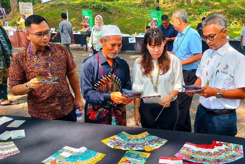 Sahariman (dua dari kiri) bersama Yu Man (dia dari kanan) dan Suris (kanan)melihat risalah yang disediakan di festival tersebut.