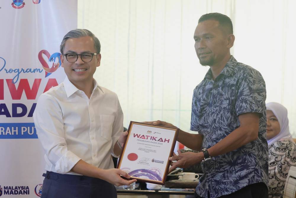 Fahmi menyampaikan watikah pelantikan Pengerusi Komuniti Madani kepada Pengerusi Komuniti Madani Pulau Gaya, Dayol Dollah (kanan), pada majlis bersama Komuniti Madani di Parlimen Putatan. Foto Bernama