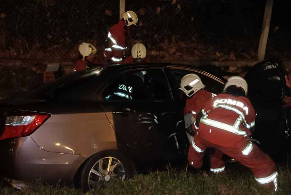 Pasukan bomba mengeluarkan mangsa yang tersepit selepas kereta dipandunya terbabas ke dalam longkang.