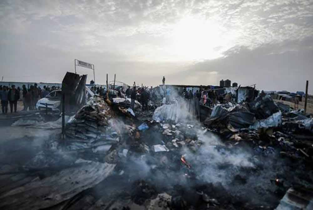 Orang ramai berkumpul di kawasan khemah yang musnah akibat serangan tentera rejim Zionis Israel di Rafah. - Foto AP