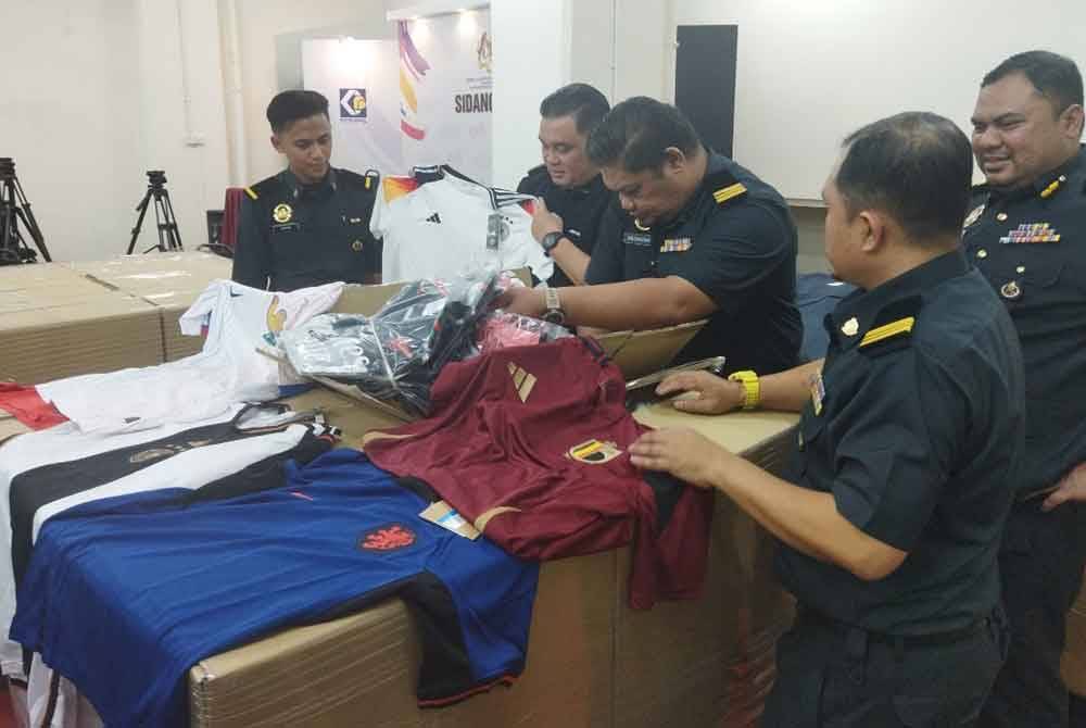 Ariffin (dua dari kiri) menunjukkan jersi tiruan yang dirampas di Jalan Petaling pada Isnin.