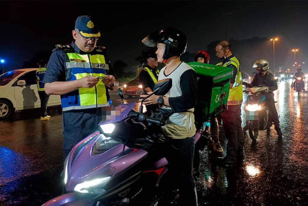 Muhammad Firdaus (kiri) memeriksa lesen pengguna jalan raya pada Operasi Khas Hari Raya Aidiladha (HRAA) di Lebuh Alor Gajah-Melaka Tengah- Jasin (AMJ) Bukit Piatu lewat malam tadi. - Foto: Bernama