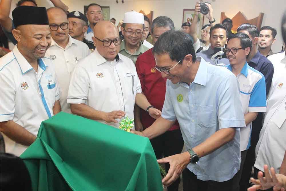 Tengku Sarafudin (kanan) menandatangani plak perasmian Galeri Padi Nuklear disaksikan Aminuddin (dua dari kiri) di Muzium Padi pada Khamis.