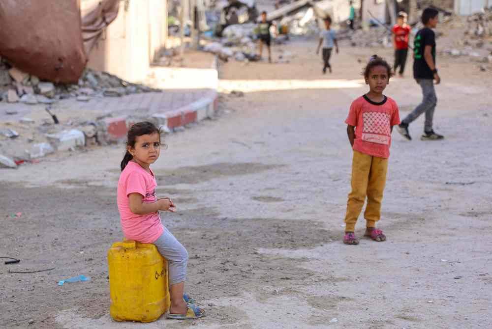 Seorang kanak-kanak Palestin duduk di atas bekas air di Kota Gaza, di tengah-tengah kekurangan air bersih semasa serangan berterusan Israel di Semenanjung Gaza. Foto AFP