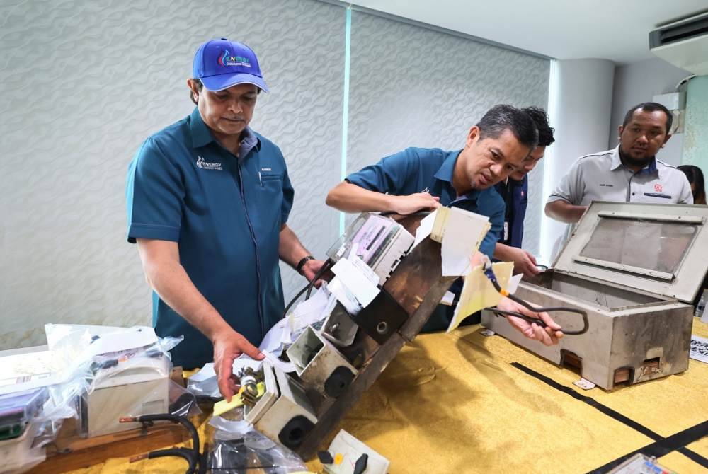 Abdul Nasir (kiri) memeriksa peralatan elektrik yang telah diubah suai untuk tujuan mencuri bekalan elektrik yang berjaya dirampas sewaktu mengadakan sidang media di Pejabat ECoS Wilayah Timur pada Khamis. Foto Bernama