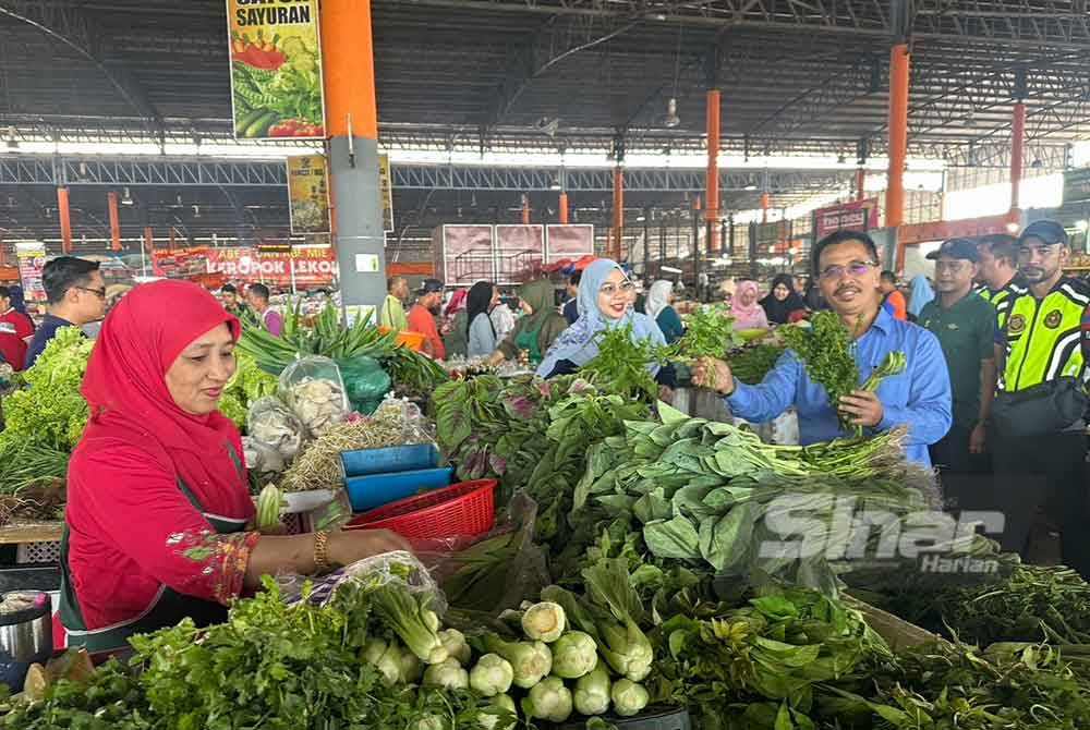 Abdul Rashid (kanan) dan Wan Faizatul Aniza (tengah) melihat sayur-sayuran yang dijual di RTC Tunjong di Kota Bharu.