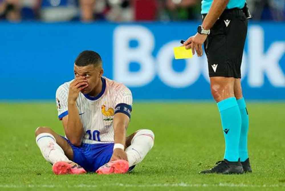 Pemain Perancis Kylian Mbappe terduduk di padang ketika pengadil memegang kad kuning semasa perlawanan kumpulan D menentang Austria dalam kejohanan Euro 2024. - Foto: AP