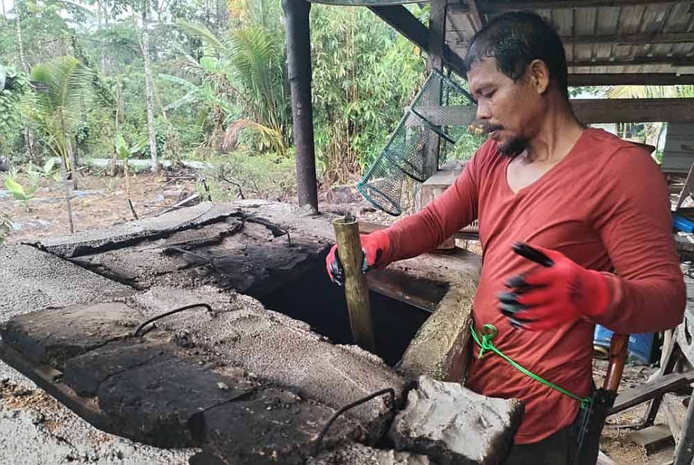 Mohd Zailani menunjukkan cara-cara memasukkan lemang ke dalam gok.