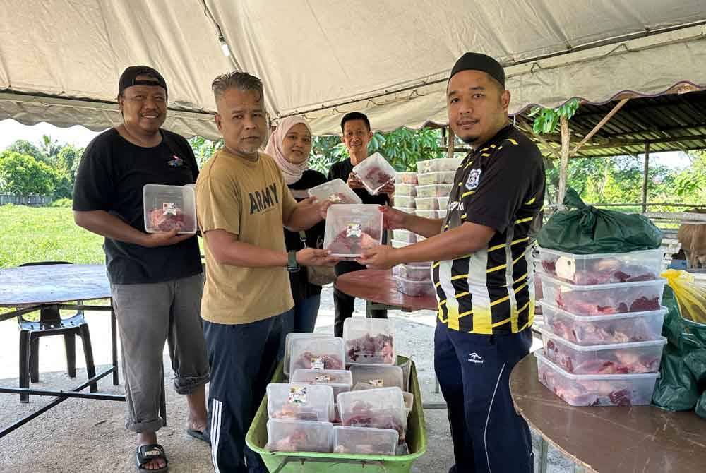 Muhammad Yatimin (kanan) menyampaikan daging korban kepada wakil asnaf di Pasir Mas.