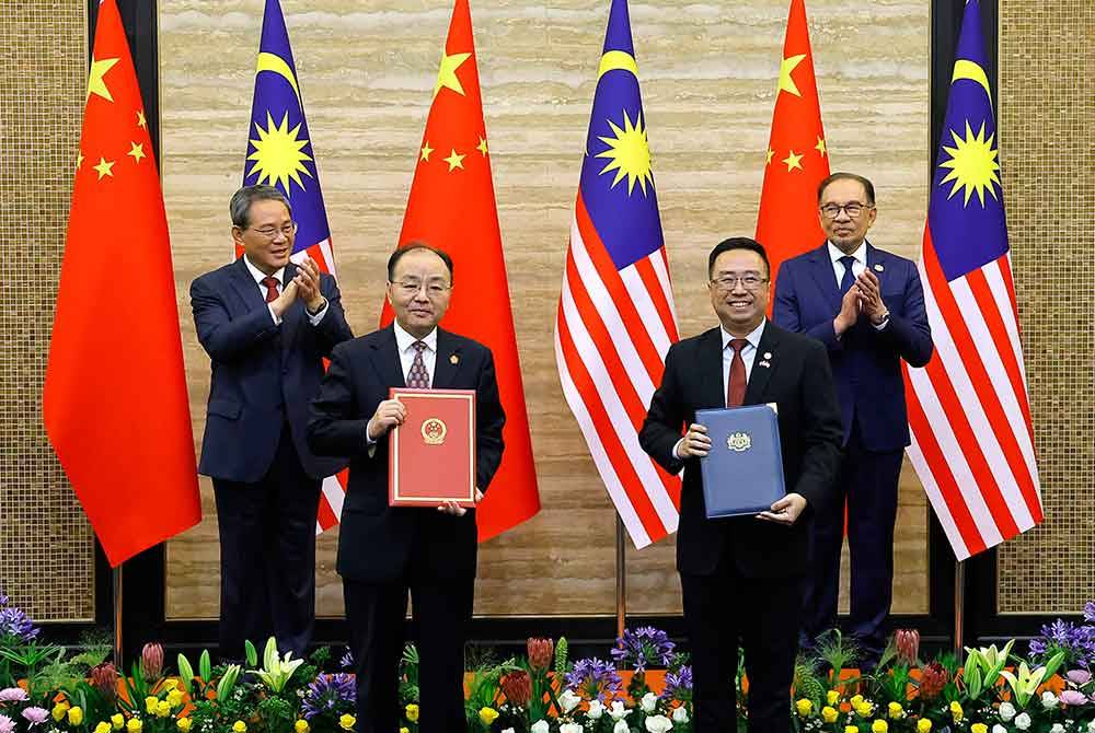 Anwar (belakang, kanan) bersama Li Qiang menyaksikan pertukaran memorandum persefahaman di antara Chang Lih Kang (depan kanan) dan Ouyang Yujing di bangunan Perdana Putra hari ini. - Foto: Bernama