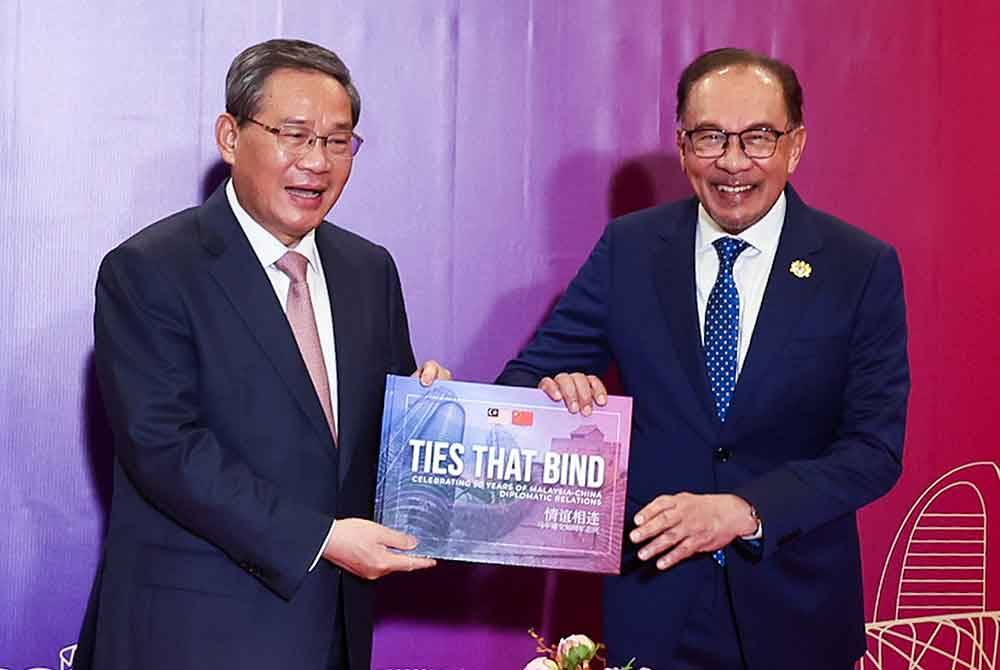 Anwar dan Qiang bertukar-tukar buku mewah bagi memperingati ulang tahun hubungan diplomatik ke-50 antara Malaysia dan China. - Foto: Bernama