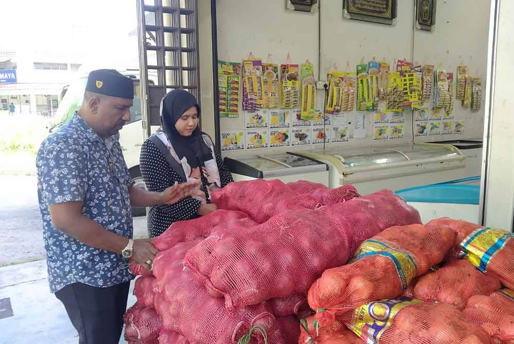 Fauziah (kanan) memeriksa stok barang-barang yang sampai di kedainya di Tasek di sini.