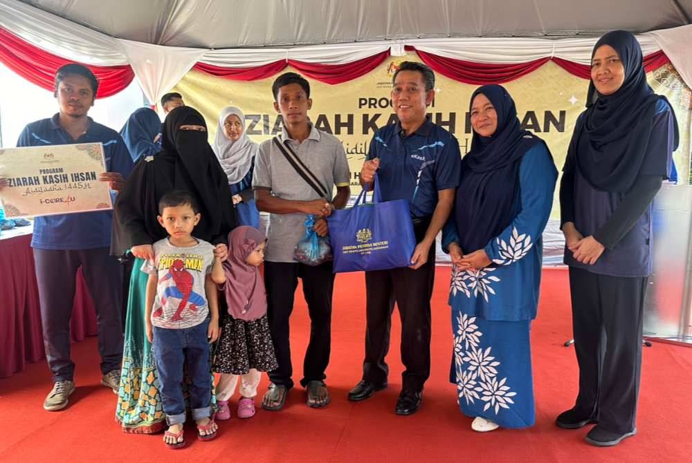 Jasri (tiga dari kanan) menyampaikan daging korban dan pek makanan kepada keluarga asnaf di Kota Bharu pada Khamis.