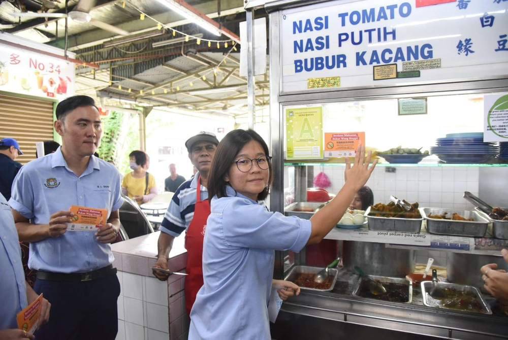 Soo Siang meletakkan pelekat peringatan mengenai sami palsu di salah sebuah gerai di Kompleks Batu Lanchang pada Khamis.