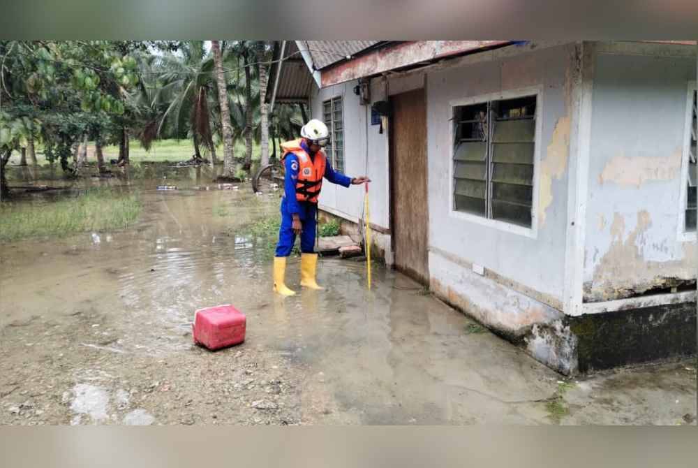 Petugas APM memeriksa keadaan rumah penduduk yang dilanda banjir kilat. Foto APM Pontian