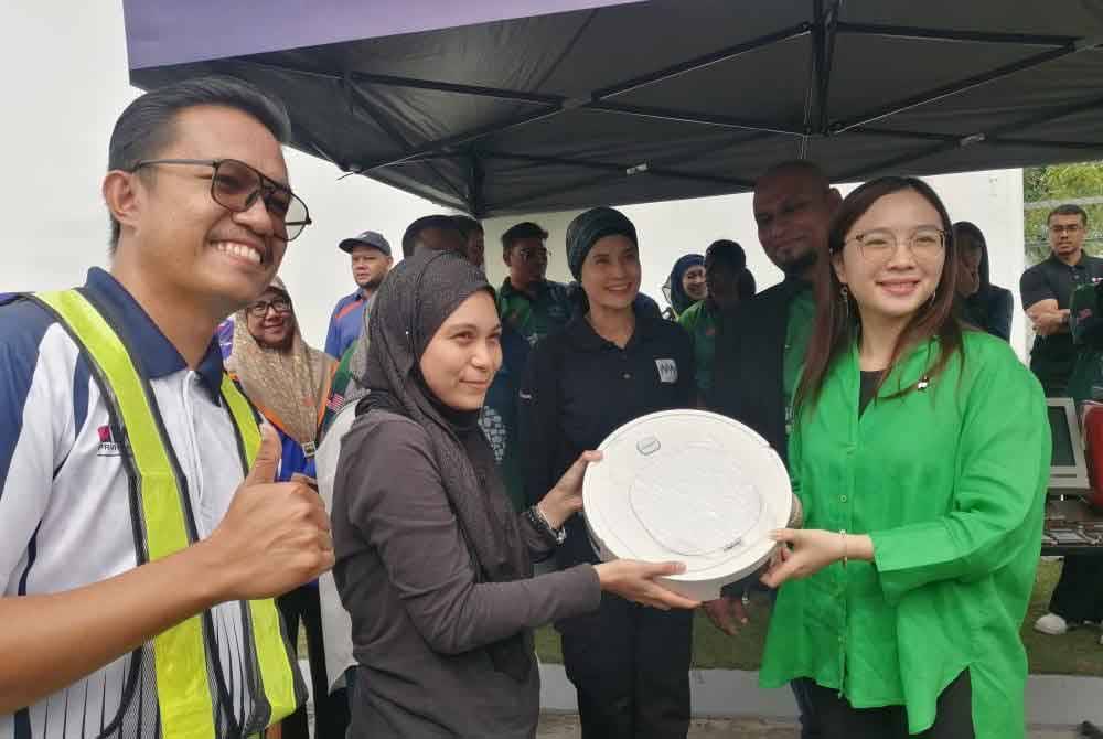 Jamaliah (kanan) bergambar bersama salah seorang penduduk yang menghantar e-waste di program pengumpulan e-waste secara pandu lalu di stesen minyak Petron Rinching di sini pada Sabtu.