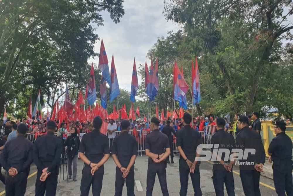 Anggota polis berkawal berhampiran tempat penyokong Pakatan Harapan di pusat penamaan calon di Dewan Serbaguna Jawi pada Sabtu.