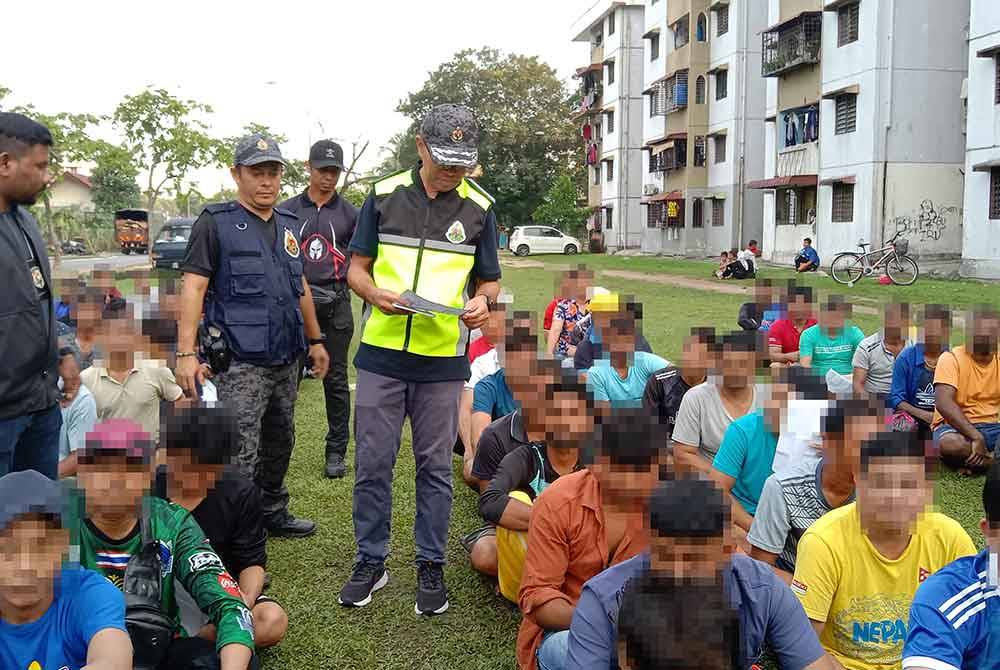 Khairrul Aminus (tengah) memeriksa dokumen warga asing yang ditahan dalam operasi dijalankan di kawasan perumahan flat Jalan Sultan Abdul Samad di Bandar Sultan Suleiman pada Ahad.