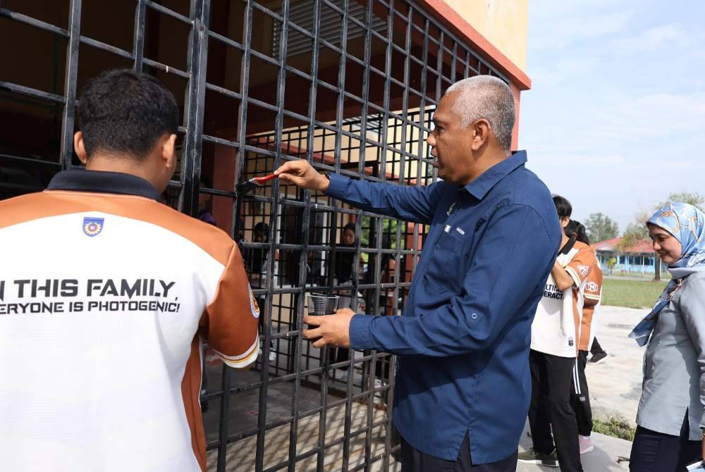 Khairudin (dua dari kiri) turut mengecat bersama-sama pelajar IKBN Seri Iskandar selepas merasmikan Program Cakna@Impak IKBN Seri Iskandar di Dewan Serbaguna Taman Iskandar Perdana, Seri Iskandar di Parit pada Selasa.