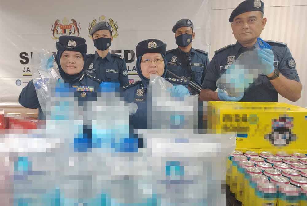 Norlela (tengah) menunjukkan rampasan air zamzam dalam serbuan di sebuah gudang di Shah Alam, Mei lalu.