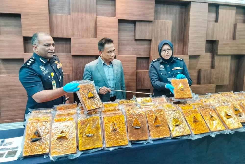 Fisol (tengah) menunjukkan ketulan mampat ganja yang dirampas di inap desa berkenaan.