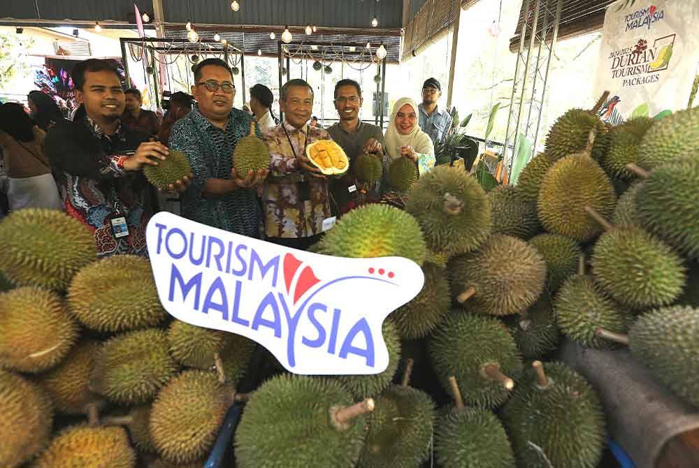 Saidi (tengah) menunjukkan buah durian yang terdapat di Broga Orchard Hill pada Khamis.