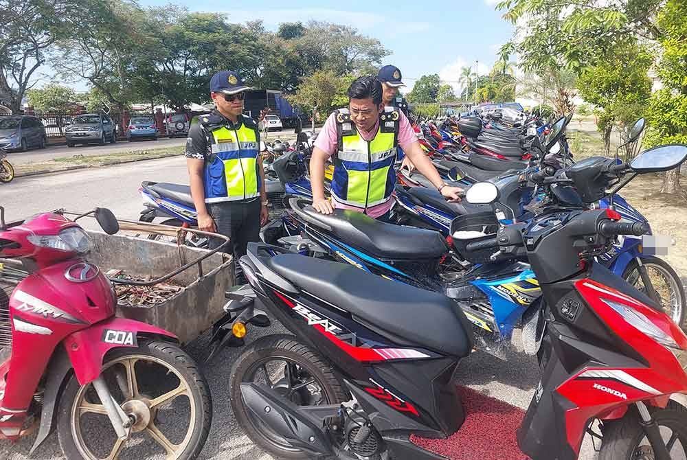 Mohd Zamri (tengah) melihat motosikal yang disita.