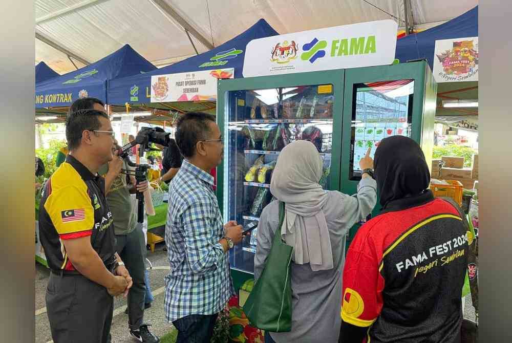 Ketua Pengarah FAMA, Abdul Rashid Bahri (dua dari kiri) menyantuni seorang pengunjung membeli sayur-sayuran menerusi mesin layan diri yang disediakan di tapak FAMA Fest 2024 @ Negeri Sembilan.