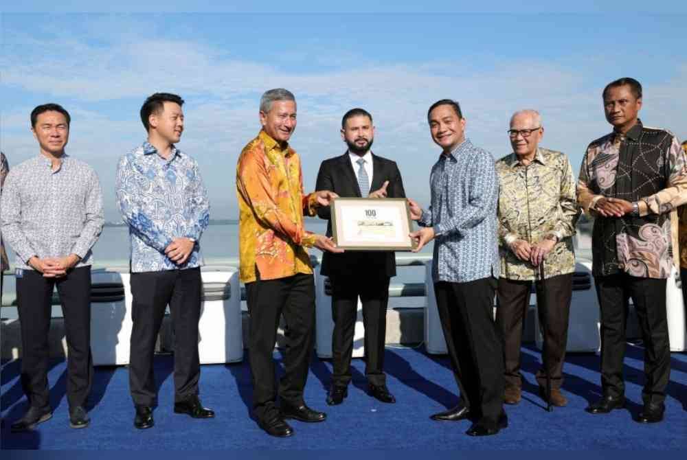 Tunku Mahkota Ismail (tengah) berkenan menyaksikan penyerahan cenderahati daripada Menteri Luar Singapura Dr Vivian Balakrishnan (tiga dari kiri), kepada Menteri Besar Johor, Datuk Onn Hafiz Ghazi (tiga, kanan) sempena Sambutan 100 Tahun Tambak Johor di tengah tambak sempadan Johor dan Singapura hari ini. Foto Bernama