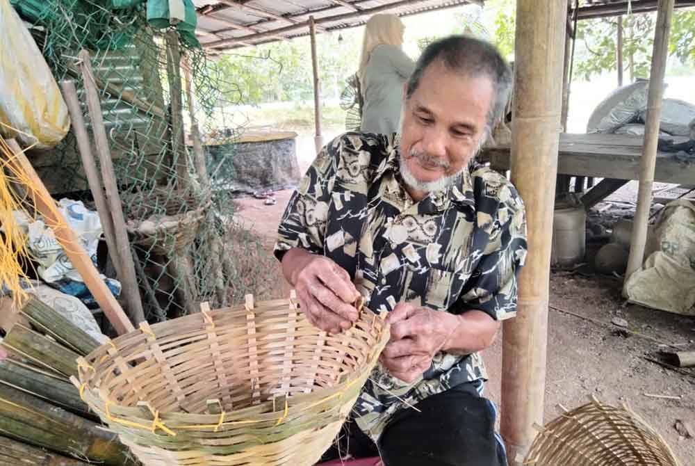 Mohd Noor mengayam buluh untuk dijadikan sangkak.