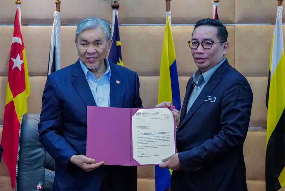 Ahmad Zahid (kiri) menyampaikan watikah pelantikan kepada Zainal Azni dalam satu mesyuarat di Putrajaya pada Jumaat. Foto KKDW