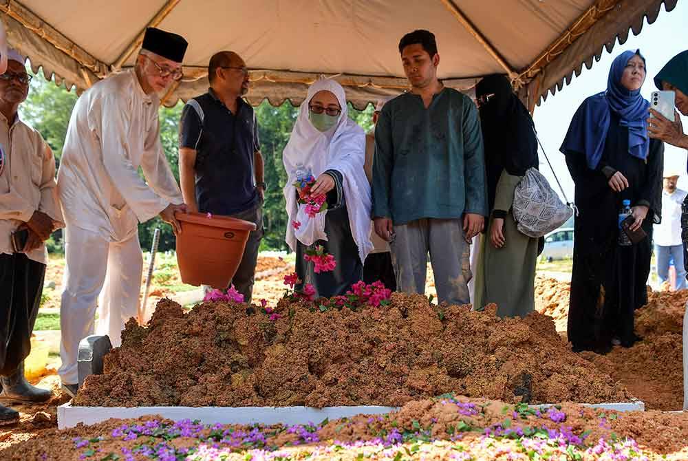 Anak bongsu Allahyarham, Nur Aini menabur bunga mawar di atas pusara bapanya selepas selesai urusan pengebumian di Tanah Perkuburan Islam Seksyen 9 Kota Damansara pada Sabtu. Foto Bernama