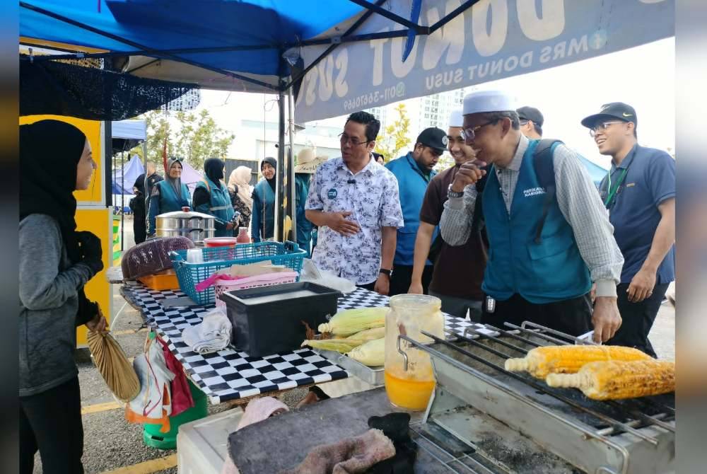 Abidin (empat kanan) semasa menyantuni para peniaga di Simpang Ampat, Sungai Bakap pada petang Isnin.