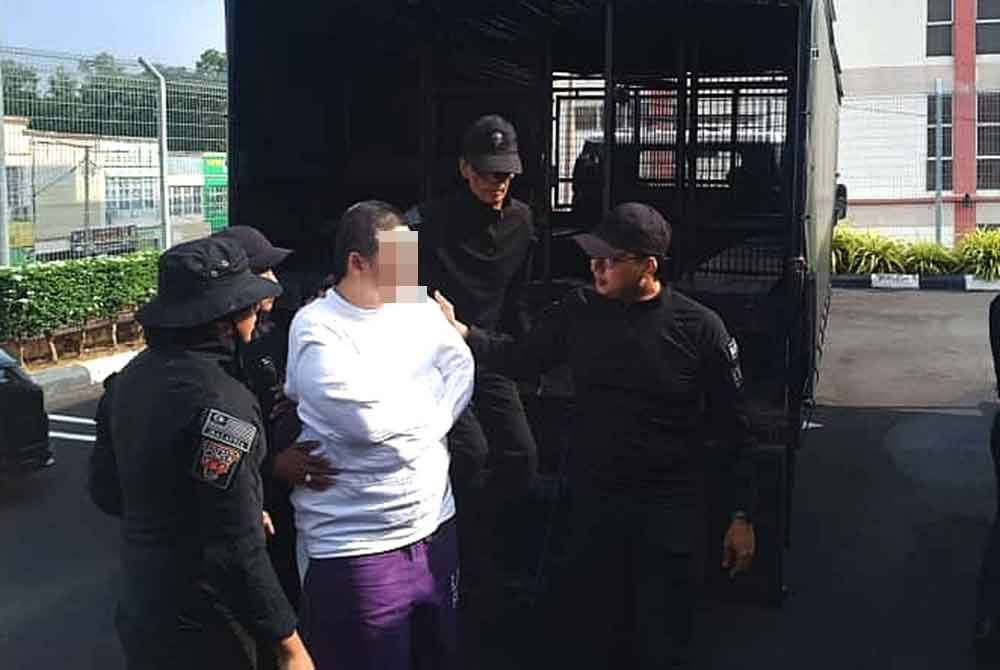 Tertuduh diiring polis ketika hadir ke mahkamah.