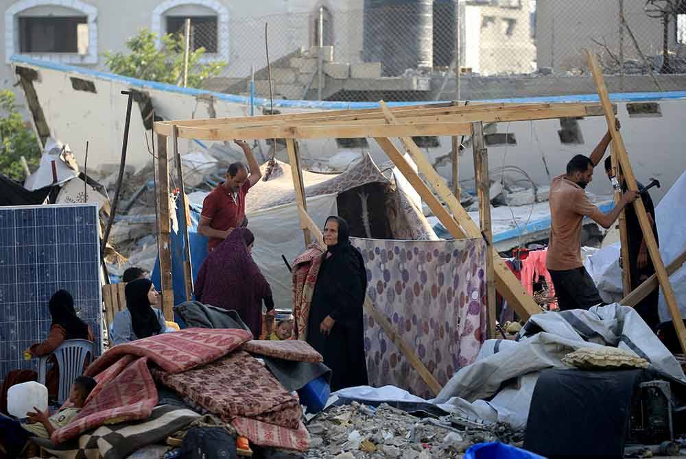 Penduduk Gaza yang terpaksa meninggalkan timur Khan Yunis mendirikan khemah sementara di tempat berlindung baharu. - Foto AFP