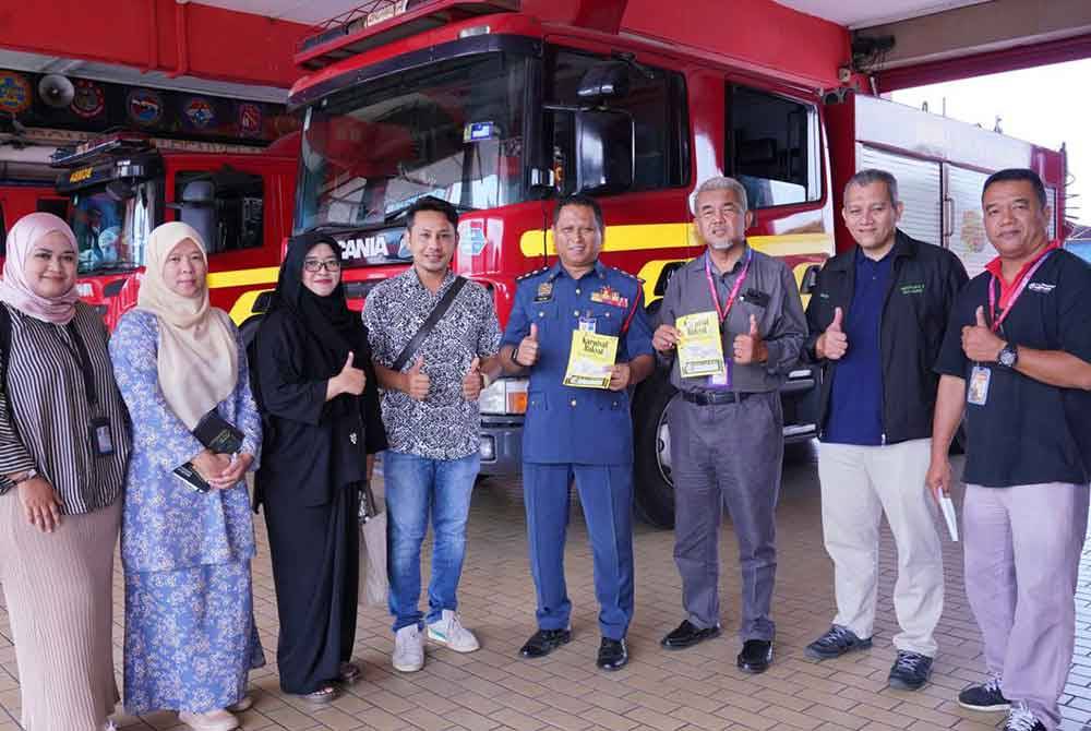 Pihak Karangkraf bergambar dengan Ahmad Nazmi (tengah) di Balai Bomba dan Penyelamat Seksyen 15, di sini pada Rabu.