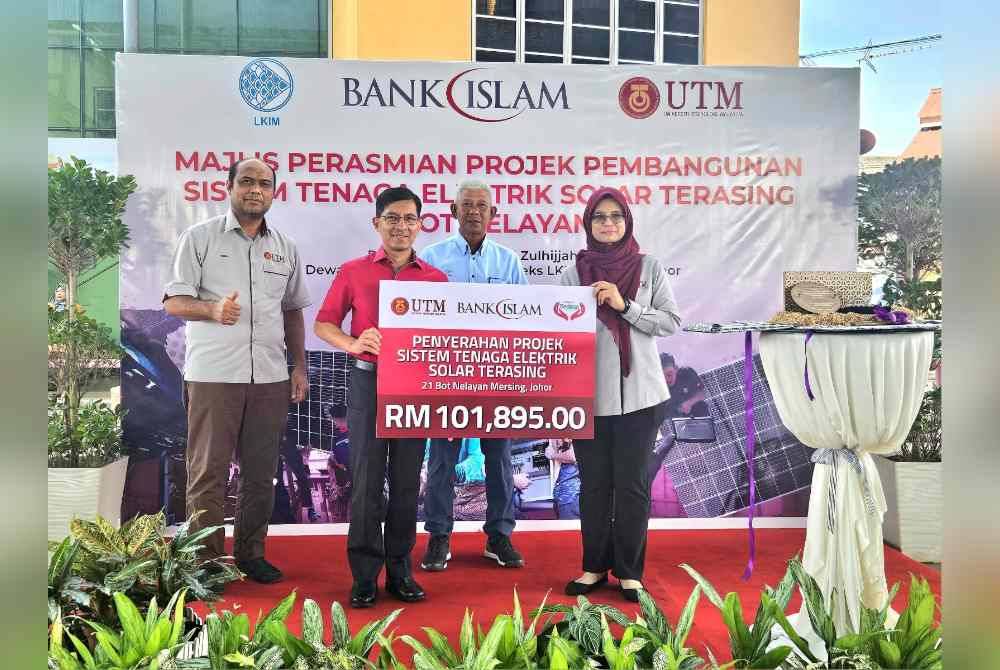 Ketua Pegawai Eksekutif Kumpulan Bank Islam, Datuk Mohd Muazzam Mohamed (dua dari kiri) menyerahkan replika cek sumbangan Sadaqa House bernilai lebih RM100,000 kepada Ketua Projek Pembangunan Sistem Tenaga Elektrik Solar Terasing Bot Nelayan Universiti Teknologi Malaysia (UTM), Dr Madihah Mohd Rasid sempena Majlis Perasmian Projek Pembangunan Sistem Tenaga Elektrik Solar Terasing untuk 21 Nelayan di Mersing, Johor pada Rabu.