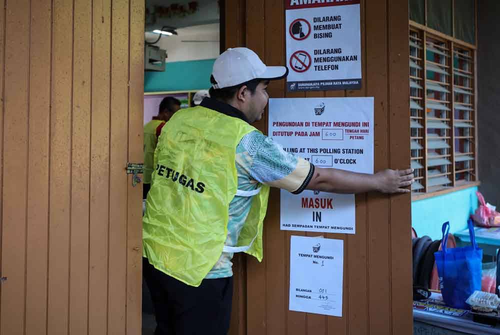 Petugas SPR menutup pintu saluran mengundi tepat pada jam 6 petang menandakan tamat proses pengundian bagi PRK N.20 Sungai Bakap di Sekolah Kebangsaan Jawi hari ini. Foto Bernama