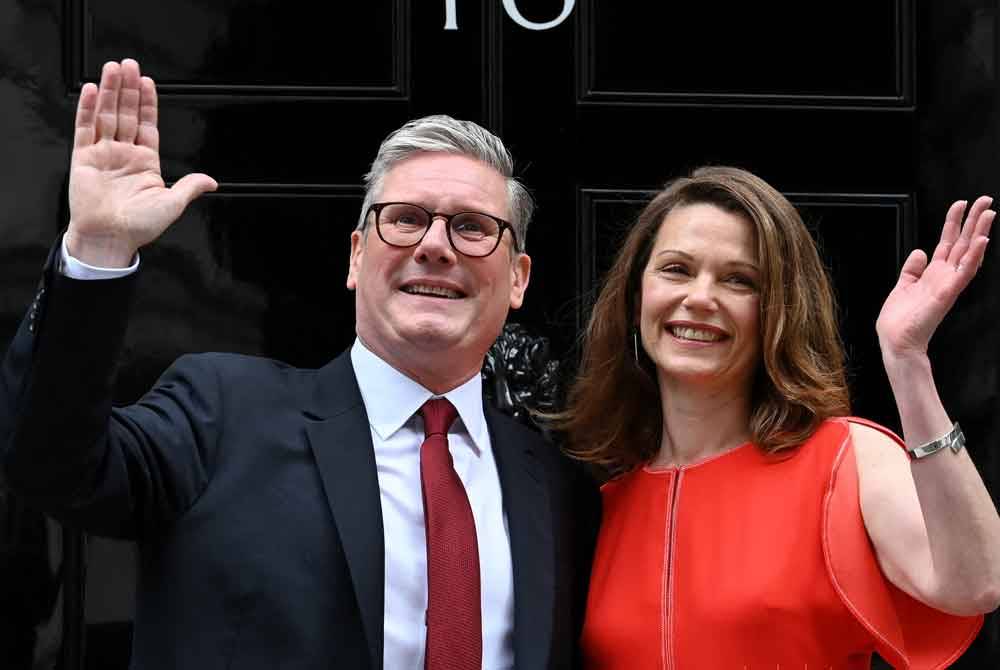 Starmer dan isterinya, Victoria melambai tangan di Downing Street, London selepas dilantik menjadi PM Britain baharu. - AFP