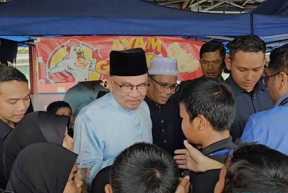 Perdana Menteri Datuk Seri Anwar Ibrahim "diserbu" sekumpulan murid sekolah ketika sedang menikmati makan tengah hari di gerai An-Najah Presint 9 di sini, pada Jumaat sebelum menunaikan solat Jumaat. Foto Bernama