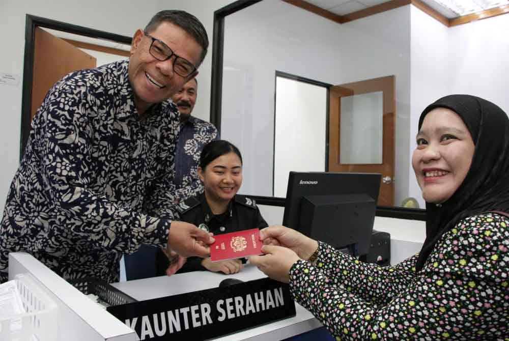 Saifuddin menyerahkan pasport yang diperbaharui kepada seorang pelanggan di kaunter Pejabat Pasport Jabatan Imigresen Sabah di KKIA.